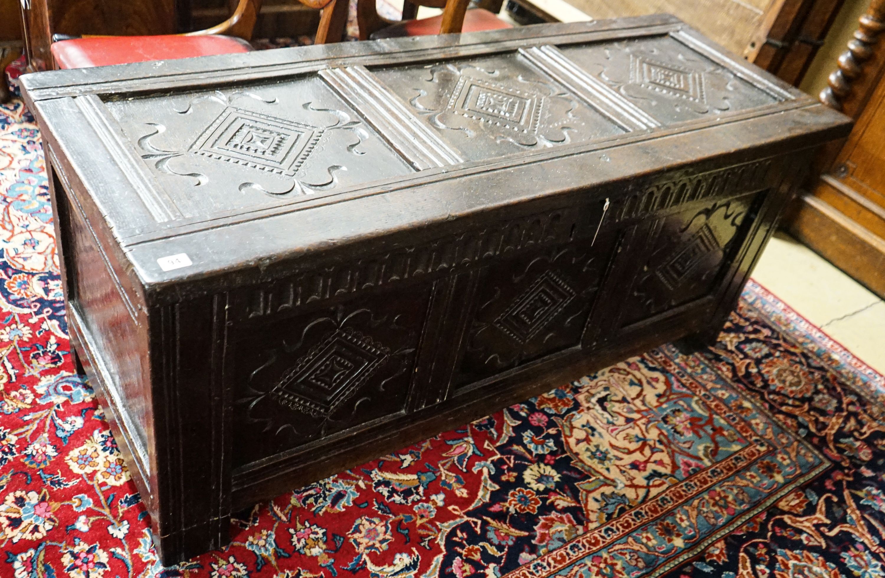 A late 17th/early 18th century carved and panelled oak coffer with hinged lid, width 136cm, depth 51cm, height 58cm